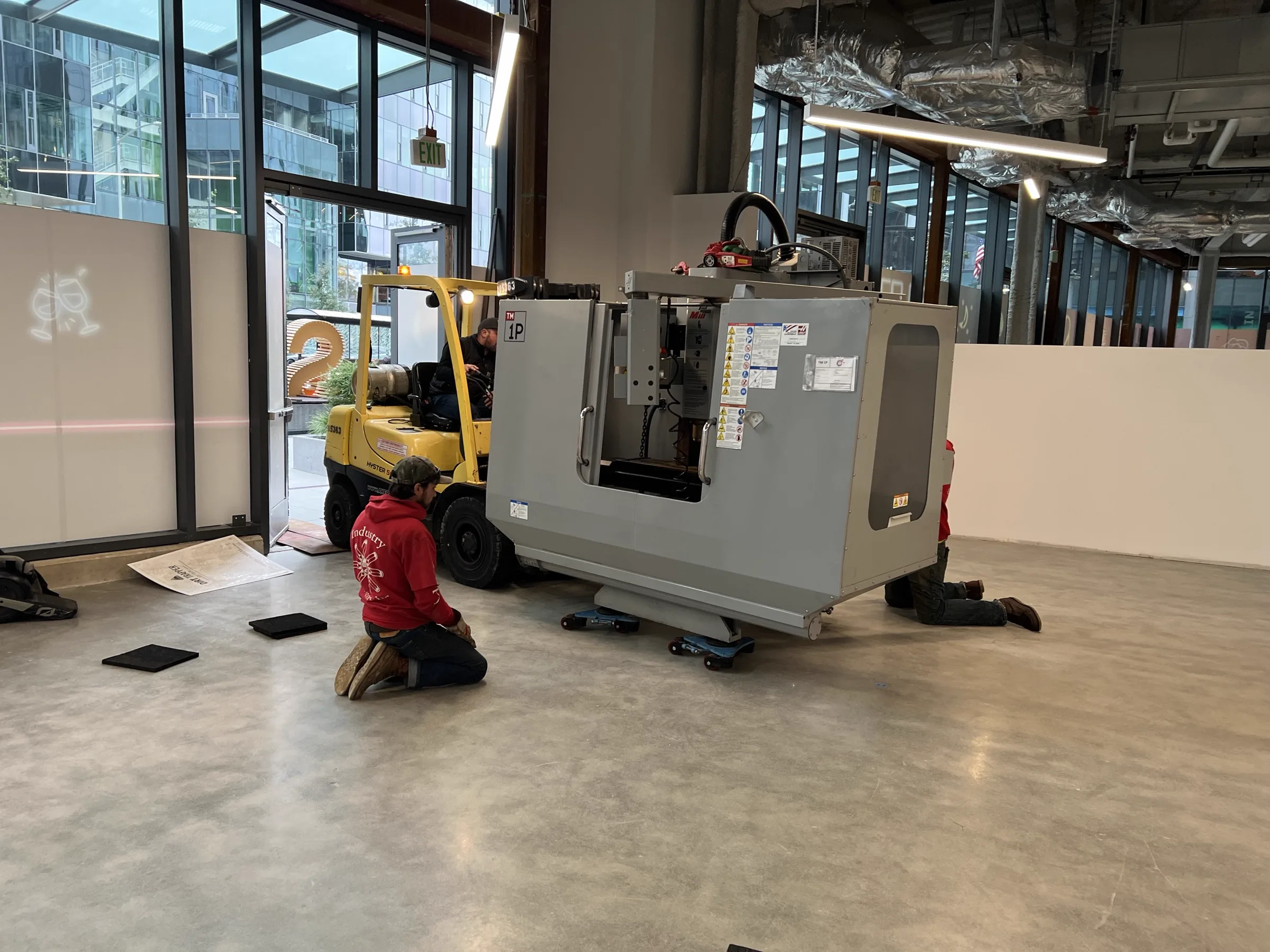 CNC mill being installed inside studio with forklift