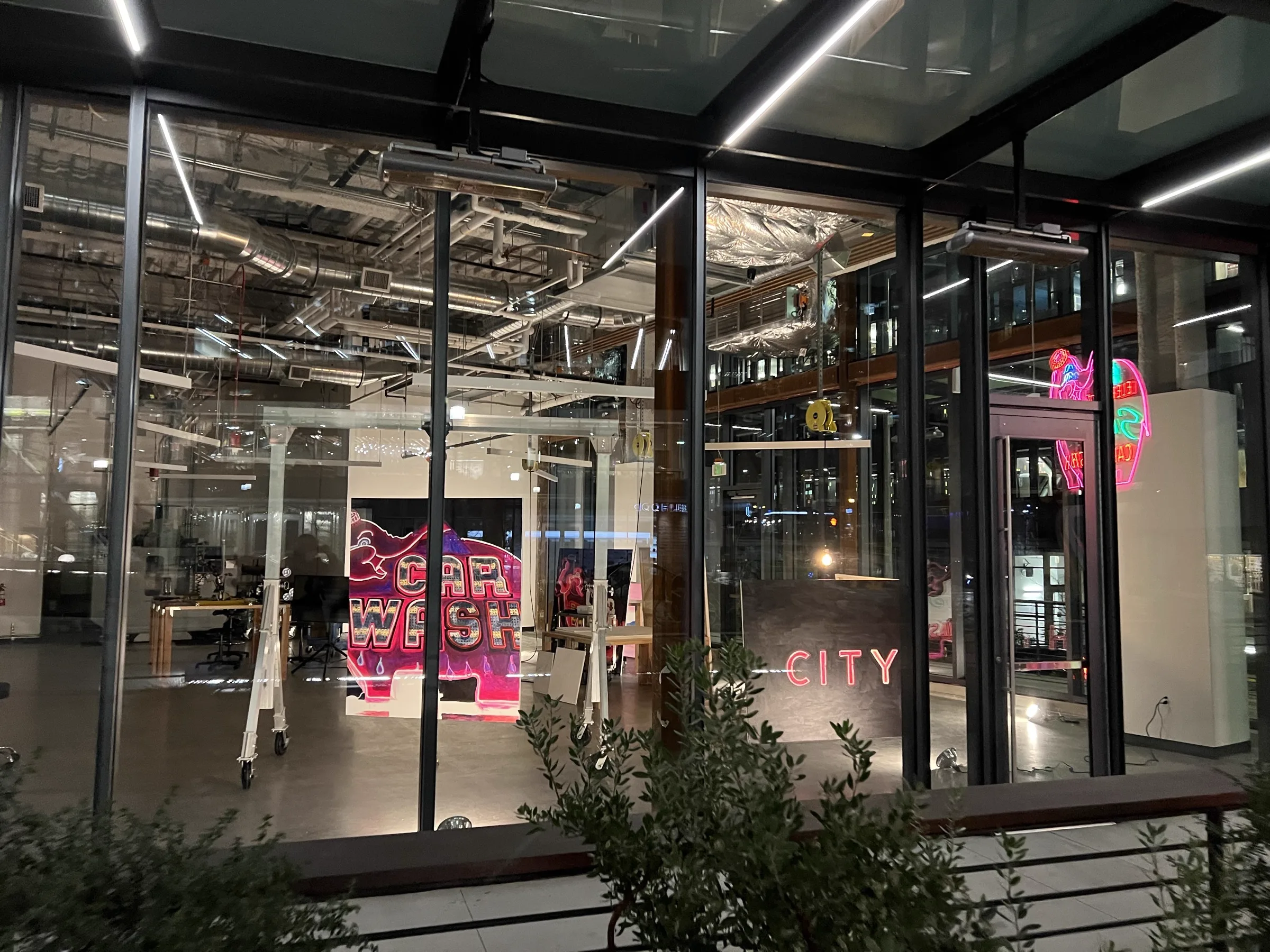 Studio interior glowing through glass at night with Car Wash painting visible