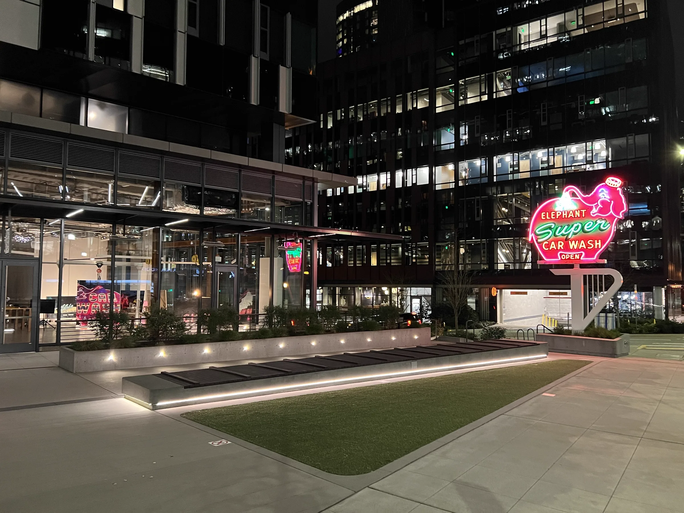 Studio at night across plaza with Elephant Super Car Wash neon sign visible