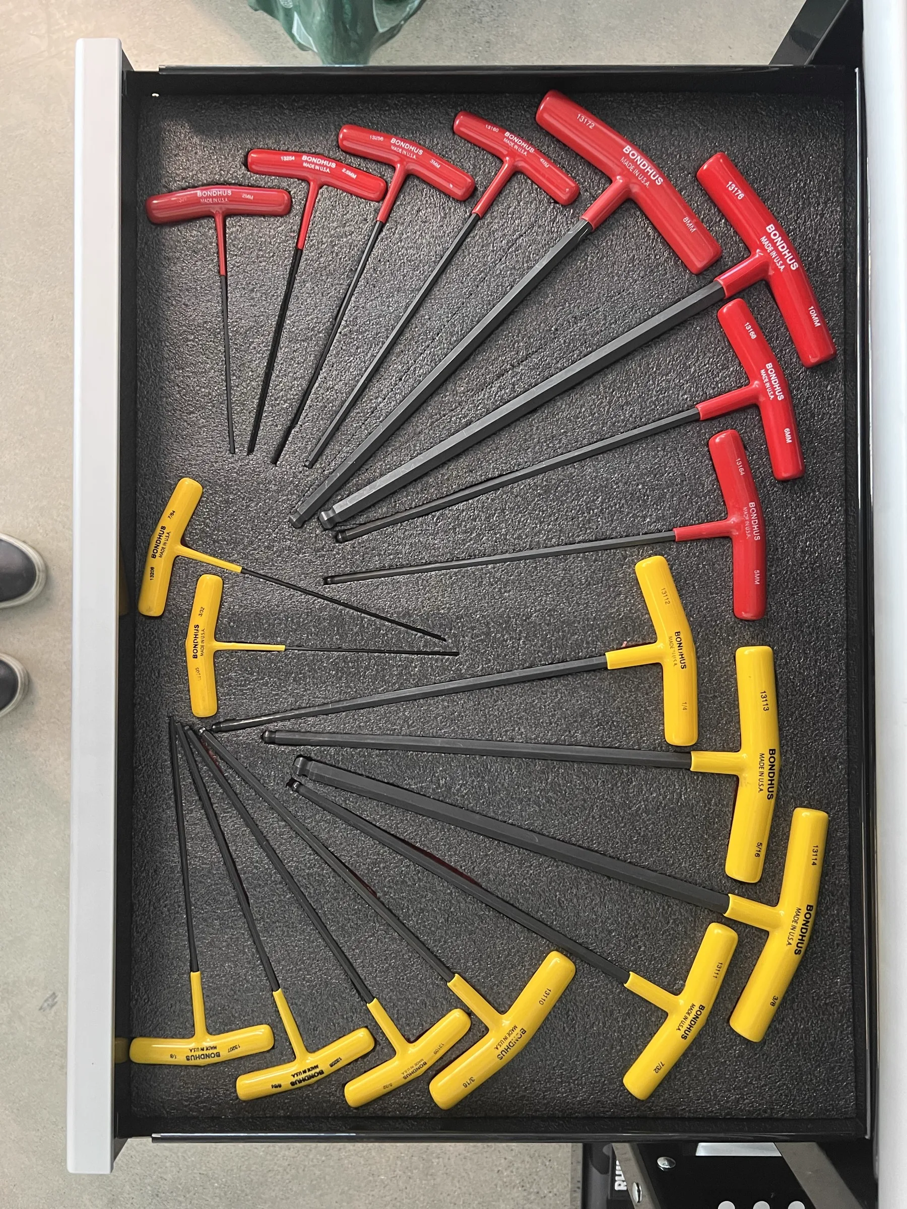 A drawer of red and yellow T-handle Allen wrenches arranged in a perfect fan