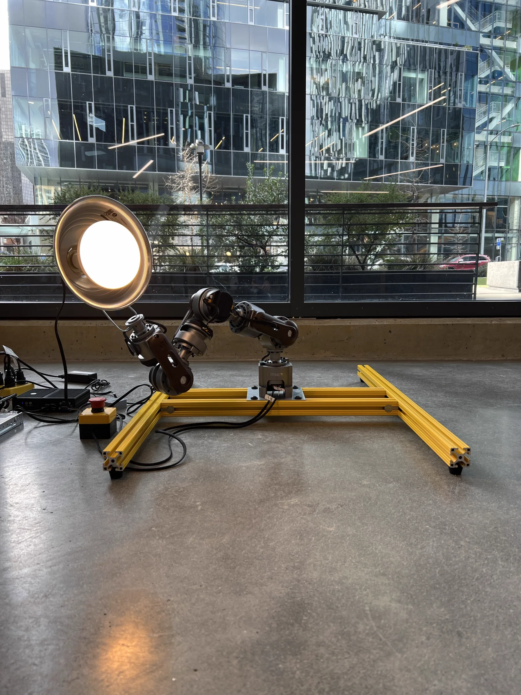 Waldorf the seven-axis robotic arm at the studio window holding a vintage industrial lamp